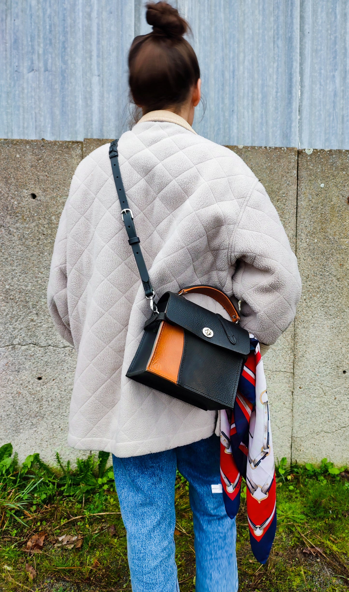 Une femme porte un sac en cuir de selle recyclé élégant aux inspirations de sac Kelly de chez Hermes